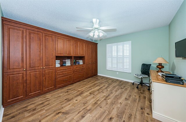 home office with light wood-type flooring, ceiling fan, and a textured ceiling