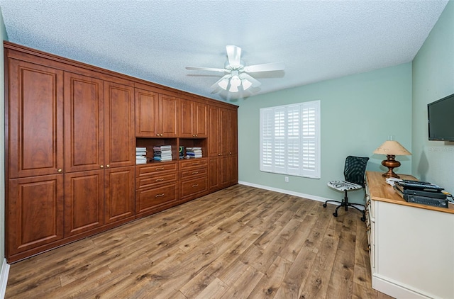 home office featuring ceiling fan, light wood-type flooring, and a textured ceiling