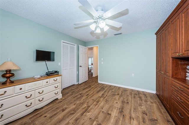 bedroom featuring hardwood / wood-style floors, a closet, ceiling fan, and a textured ceiling