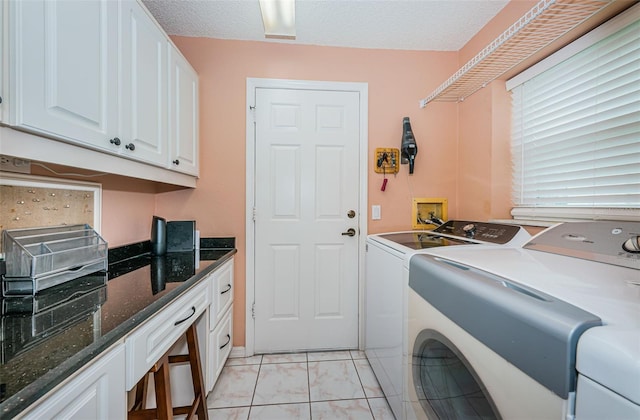 laundry area featuring separate washer and dryer, cabinets, and a textured ceiling