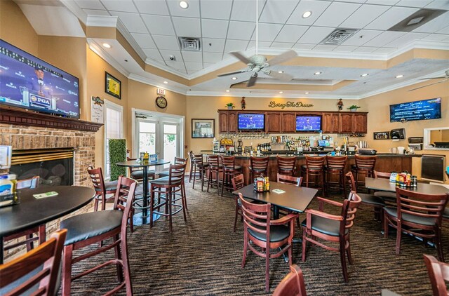 carpeted dining room featuring a high ceiling, a fireplace, crown molding, and ceiling fan