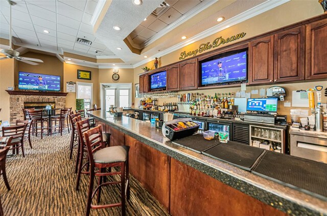 bar featuring dark carpet, ceiling fan, crown molding, and a tray ceiling