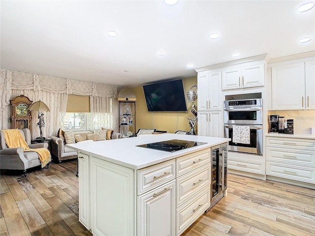 kitchen featuring black electric cooktop, open floor plan, double oven, wine cooler, and light wood finished floors