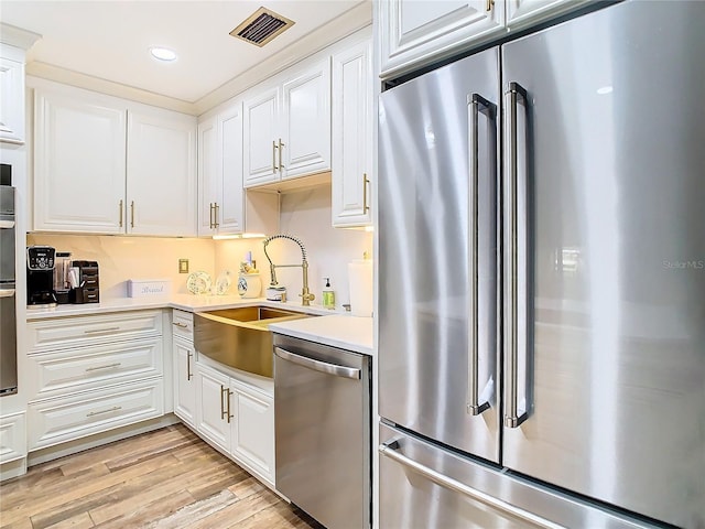 kitchen featuring stainless steel appliances, a sink, light countertops, white cabinets, and recessed lighting