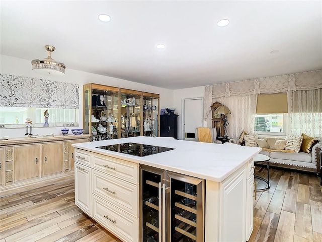 kitchen with a kitchen island, black electric cooktop, light wood-type flooring, and beverage cooler