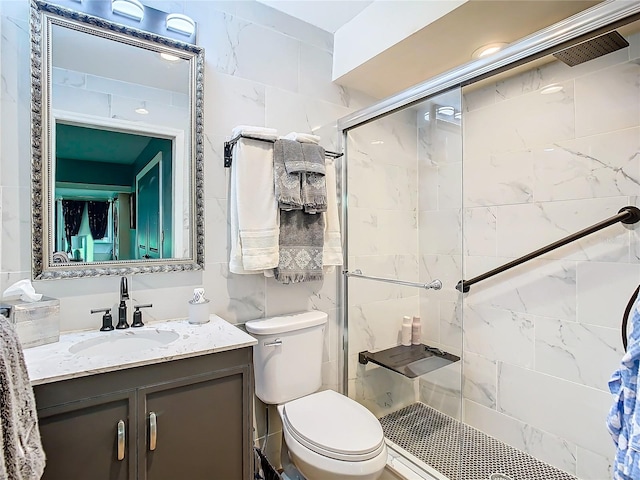 bathroom with toilet, tile walls, vanity, and a shower with shower door