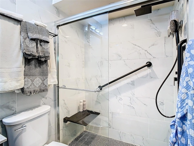 bathroom featuring tile walls, a shower with shower door, and toilet