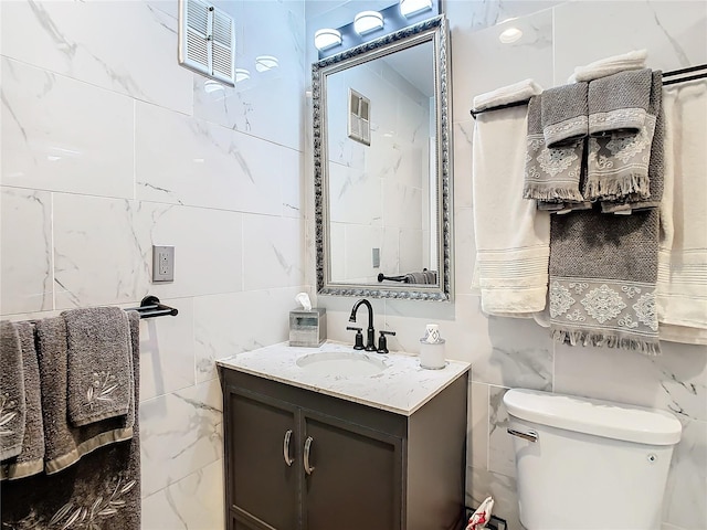bathroom with tile walls, vanity, and toilet