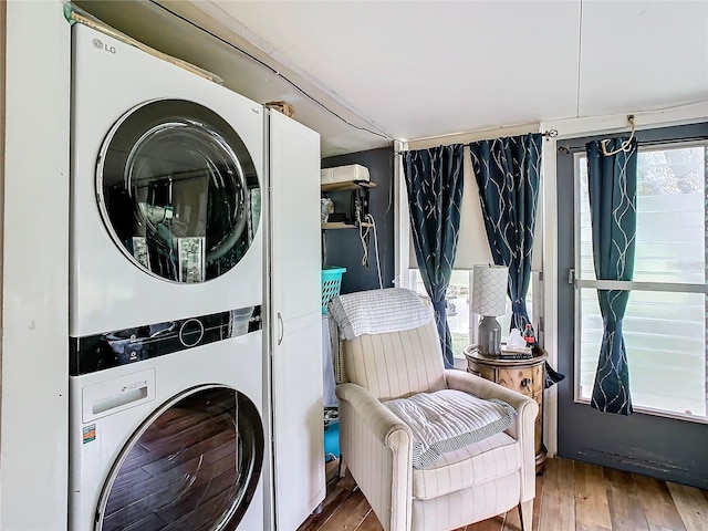 clothes washing area with stacked washer / drying machine and wood finished floors