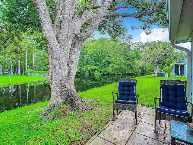 view of green lawn with a water view and a patio area