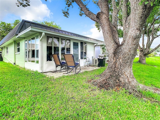 rear view of house with a lawn, metal roof, and a patio