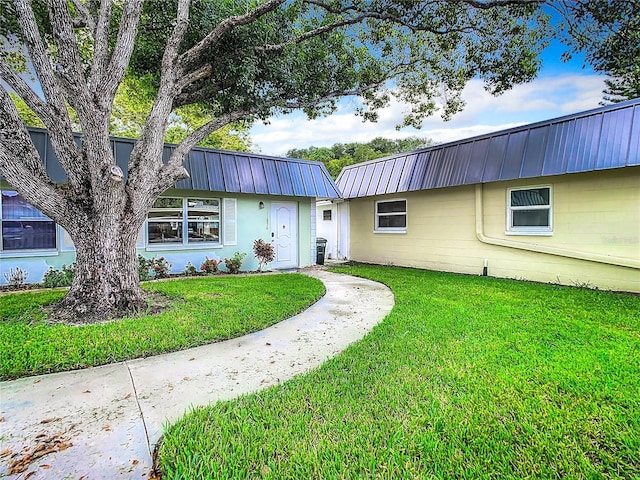 view of front facade with a front lawn, metal roof, and concrete block siding
