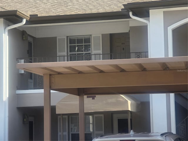 exterior space featuring a shingled roof and stucco siding