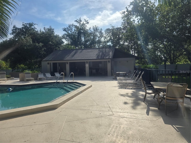 pool with a patio, fence, and an outdoor structure