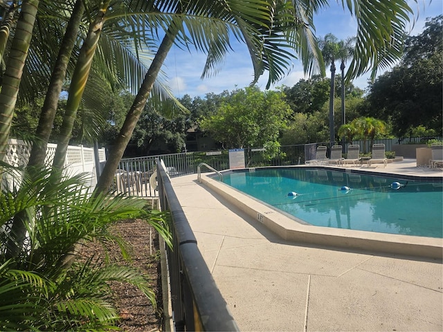 community pool with fence and a patio area