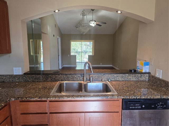 kitchen featuring stainless steel dishwasher, vaulted ceiling, ceiling fan, sink, and dark stone counters