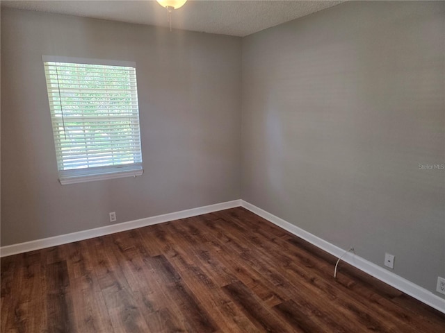 empty room with baseboards and dark wood finished floors
