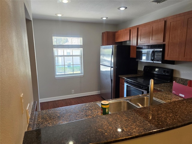 kitchen featuring brown cabinets, baseboards, black appliances, dark wood-style floors, and dark stone counters