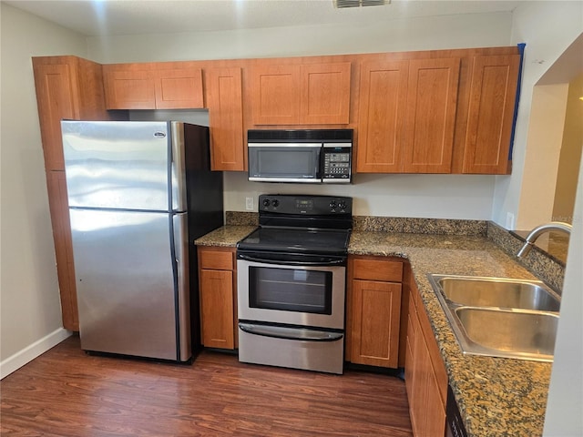 kitchen featuring a sink, brown cabinets, stainless steel appliances, and dark wood finished floors
