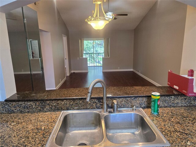kitchen featuring wood finished floors, baseboards, ceiling fan, a sink, and vaulted ceiling