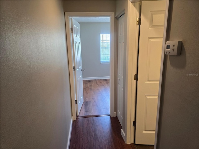 corridor with baseboards and dark wood finished floors