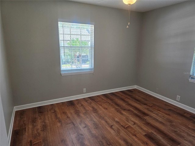 unfurnished room with baseboards and dark wood finished floors