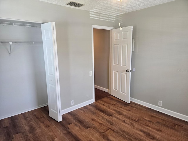 unfurnished bedroom with visible vents, baseboards, dark wood-type flooring, and a closet