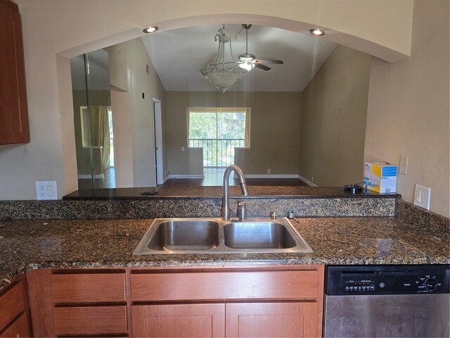kitchen with a ceiling fan, vaulted ceiling, dishwasher, a sink, and dark stone countertops
