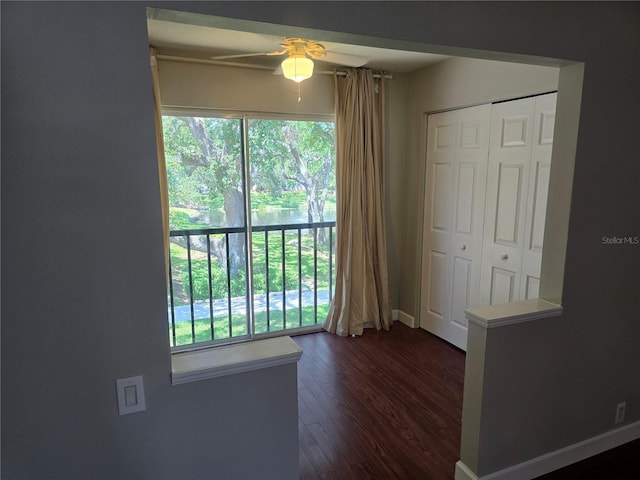 empty room with a healthy amount of sunlight, baseboards, a ceiling fan, and dark wood-style floors