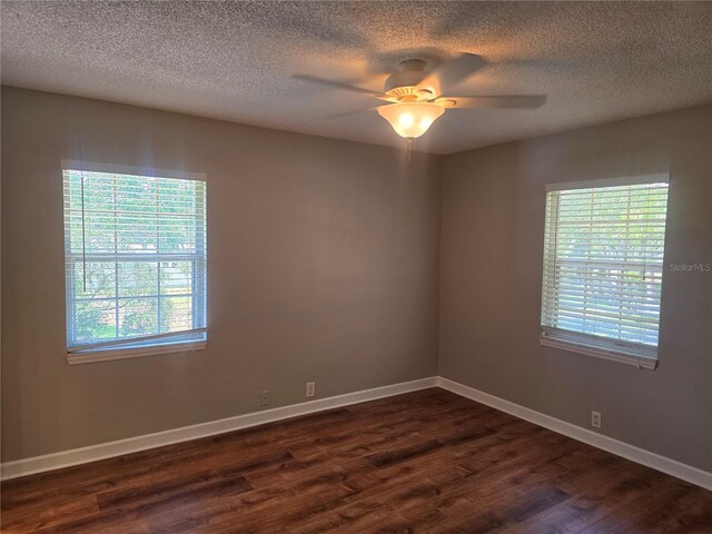 5265 E Bay Dr Unit 420, Clearwater, FL 33764 - empty room with dark wood-type flooring, healthy amount of natural light, ceiling fan, a textured ceiling, and baseboards