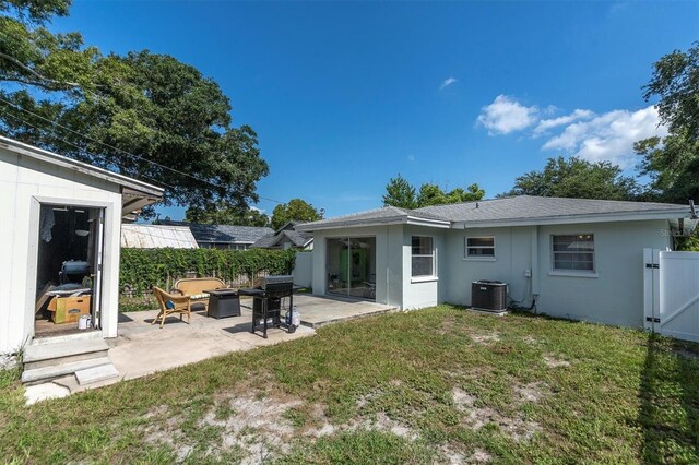 back of house with central AC, a patio area, and a lawn