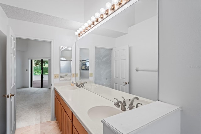 bathroom with a textured ceiling, double vanity, and tile patterned flooring