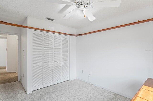 unfurnished bedroom with carpet, a closet, and ceiling fan