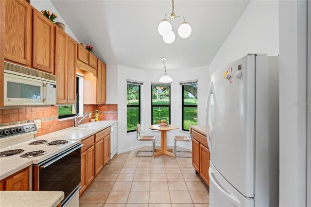 kitchen with white appliances, pendant lighting, lofted ceiling, light tile patterned floors, and decorative backsplash