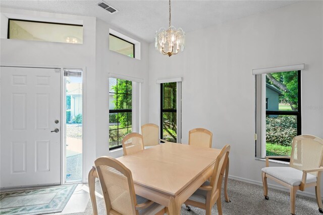 dining room featuring a towering ceiling, plenty of natural light, and an inviting chandelier