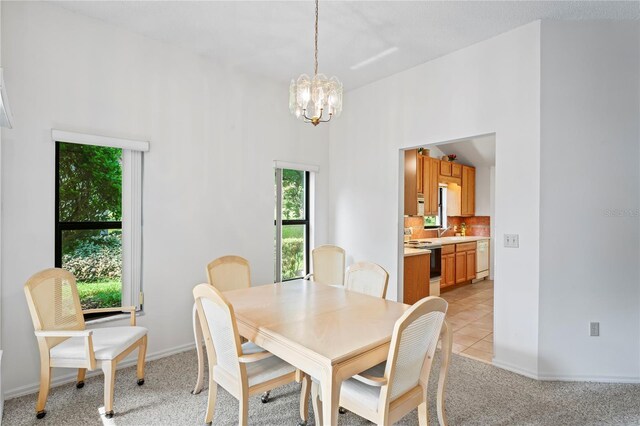 dining area with sink, a chandelier, light colored carpet, and a high ceiling