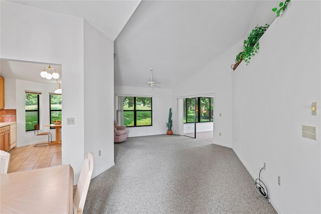 unfurnished living room with light tile patterned flooring, high vaulted ceiling, and ceiling fan with notable chandelier