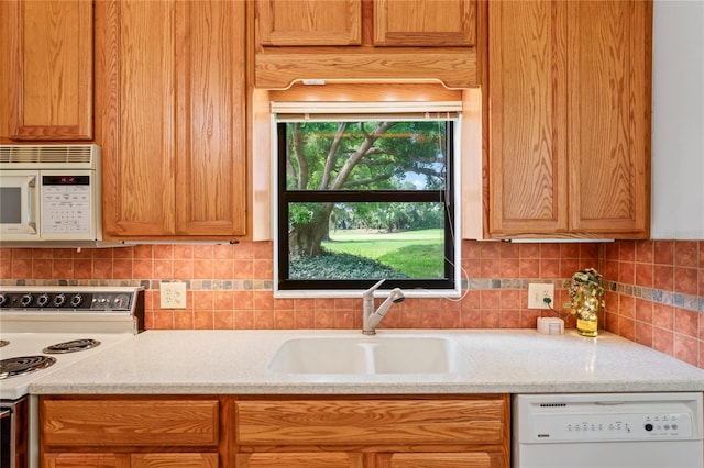 kitchen featuring light stone countertops, sink, backsplash, and white appliances