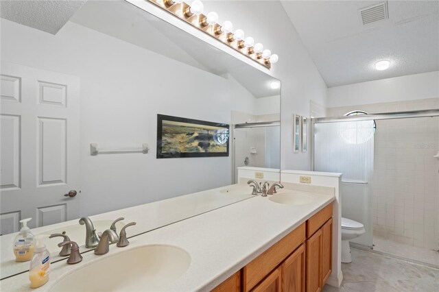 bathroom with double vanity, a textured ceiling, toilet, tile patterned flooring, and vaulted ceiling