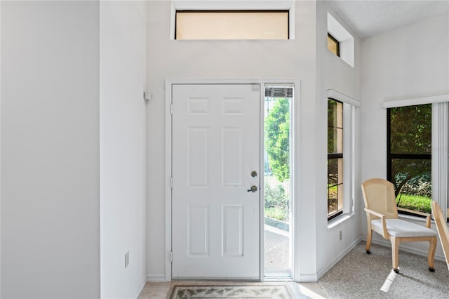 entryway featuring a towering ceiling, a textured ceiling, and plenty of natural light