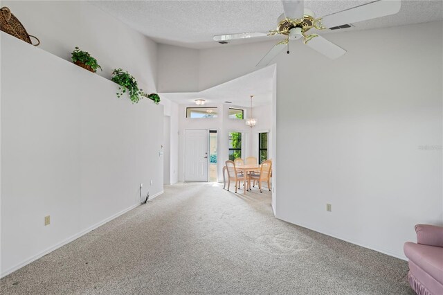 interior space featuring ceiling fan, carpet flooring, a textured ceiling, and a high ceiling