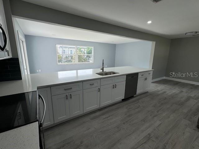 kitchen featuring hardwood / wood-style floors, stainless steel range, sink, black dishwasher, and white cabinets