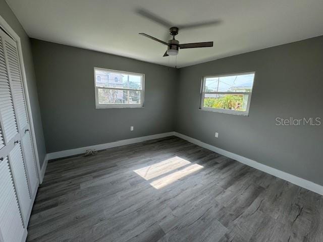 unfurnished bedroom with ceiling fan, a closet, and wood-type flooring