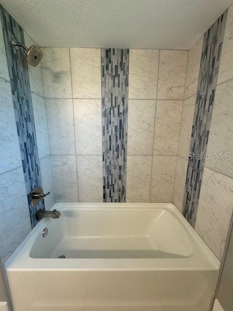 bathroom with tiled shower / bath and a textured ceiling