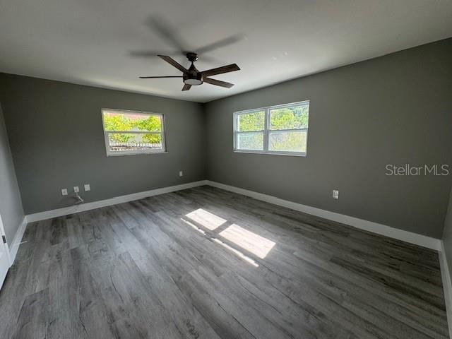 spare room featuring plenty of natural light, ceiling fan, and dark hardwood / wood-style flooring