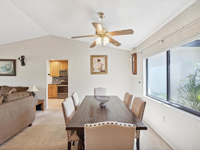 carpeted dining room with lofted ceiling, a textured ceiling, and ceiling fan