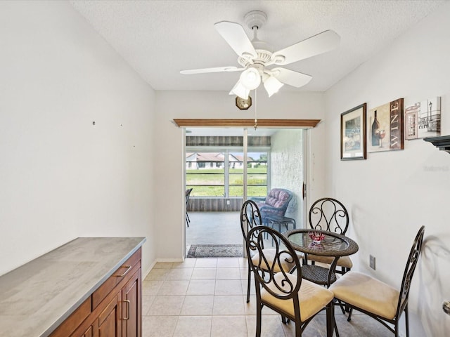 dining space with ceiling fan, a textured ceiling, and light tile patterned floors