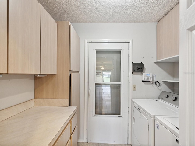 washroom with cabinets, independent washer and dryer, and a textured ceiling