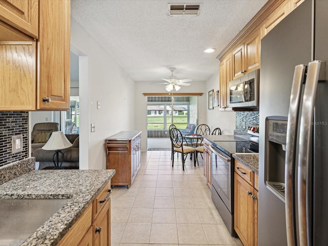 kitchen featuring sink, tasteful backsplash, light tile patterned floors, appliances with stainless steel finishes, and ceiling fan