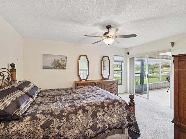 carpeted bedroom featuring ceiling fan, access to exterior, and a textured ceiling